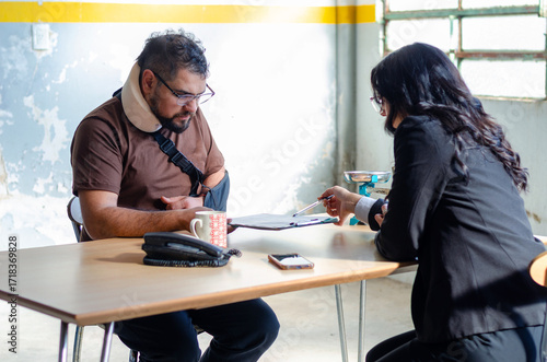Young female lawyer assist a injured man with legal problem. Lawyer showing document. Compensation for work or car accident. Legal concept. Social Worker.