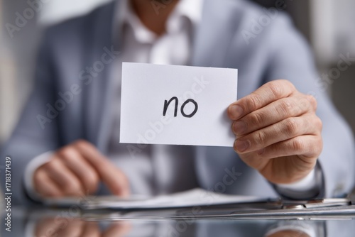 A Close-Up of a Person Holding a Card with the Word 'No' Displayed, Signifying a Firm Decision or Rejection in a Professional Context
