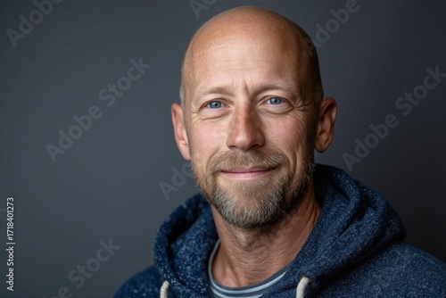 Smiling man with short hair and beard wearing a blue hoodie in studio setting Generative AI