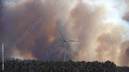 Wildfires in Portugal. A firefighting airplane drops a large stream of water over a massive wildfire, surrounded by thick smoke and intense flames. The dramatic scene captures emergency response