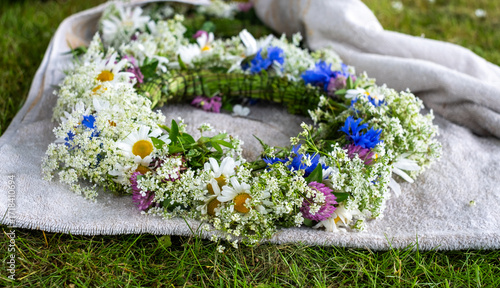 Konstfotografi Floral crown made of wildflowers and greenery rests on soft fabric, symbolizing