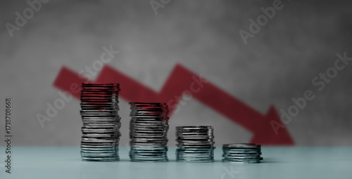 Obraz na plátne Downward red arrow with shrinking stacks of coins, depicting global recession, economic downturn, and significant financial loss
