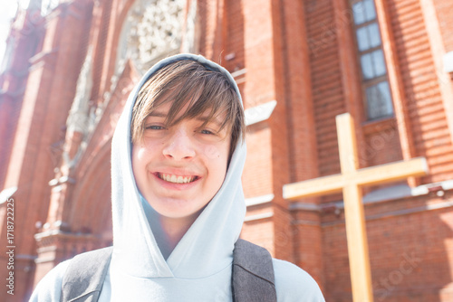 Photos Portrait of a smiling 13 year old boy with a backpack in front of a Catholic church