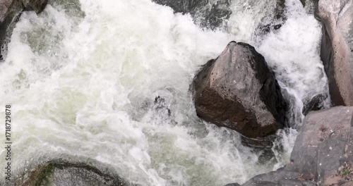 A large rock is in the middle of a rushing river