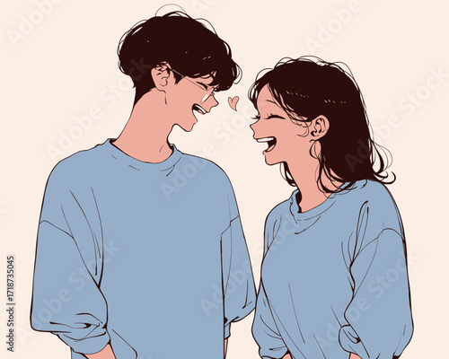 A happy couple stands close together, smiling and laughing with each other, both wearing cozy blue clothing. Their joyful expressions reflect a warm connection.