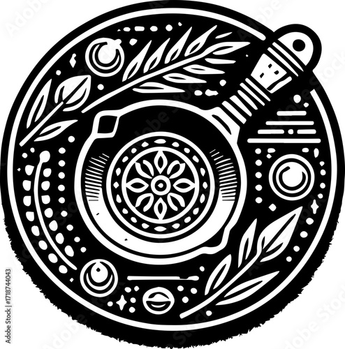 Ornate black and white circular design featuring a skillet with floral and celestial elements around it