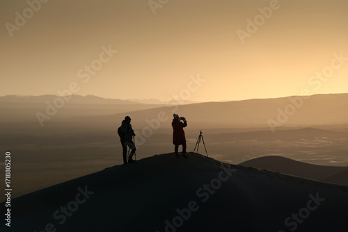 Silhouette of Two Photographers on Sand Dune in Desert during a Beautiful Sunset