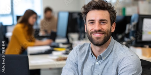 Cheerful South American CEO with a beard, looking directly at the camera in an office.
