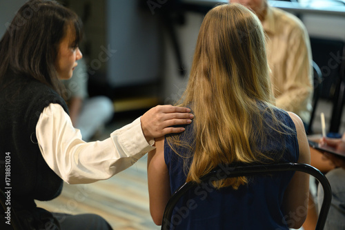 Supportive therapy session with a woman placing a comforting hand on another participant shoulder