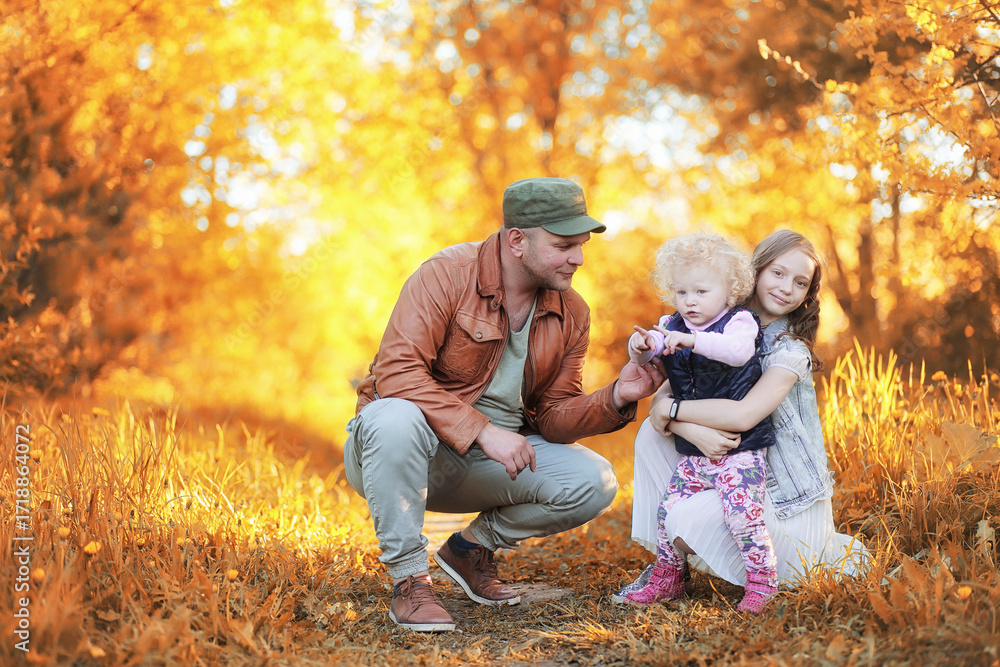 Fototapeta premium Girl walking in the autumn park. Autumn in the city, girl with dad for a walk. Parents are walking with little children. Autumn park people