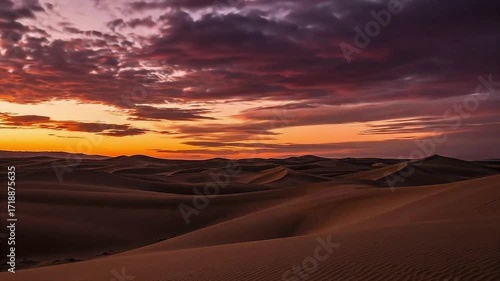 A stunning time-lapse of a fiery sunset over vast desert sand dunes, with clouds moving across the sky.