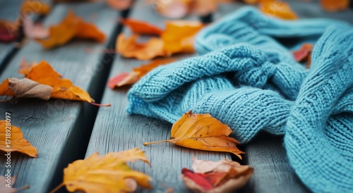 Cozy Blue Sweater Rests on Wooden Table Surrounded by Autumn Leaves in Soft N...