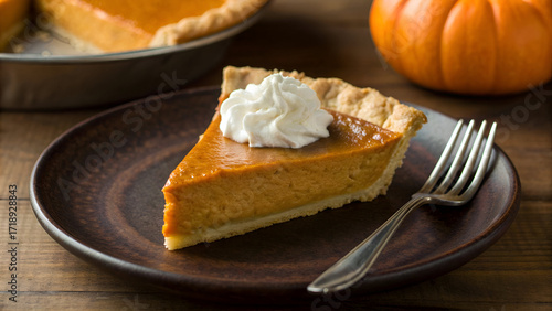 Delicious slice of homemade pumpkin pie with whipped cream perfect for Thanksgiving holiday dessert a traditional autumn treat served on a rustic wooden table