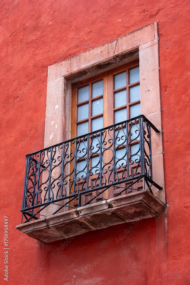 Fototapeta premium A window with a wooden frame and a metal railing. The railing is ornate and the window is open. Historic center of Queretaro City, decorations and traditions to celebrate Mexico's Independence Day, co