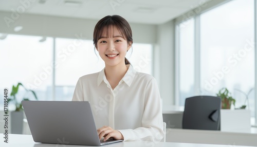 明るいオフィスで働く笑顔の若い女性社員