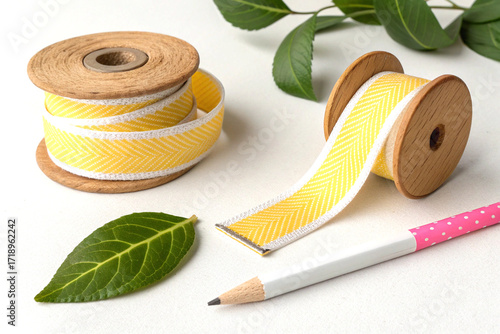 Yellow and white fabric tape with wooden spool pencil eraser and leaf