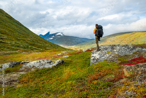 Young woman with backpack in mountains. Sarek National Park, Sweden.