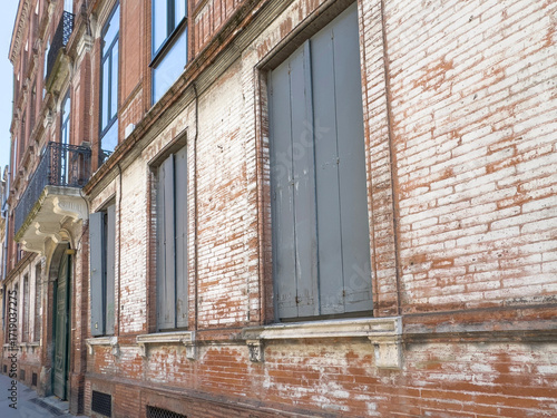 Old Red Brick Building with Weathered Gray Shutters and Vintage Facade Details