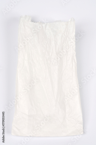A view of a crumpled white paper bag on a neutral, light gray background