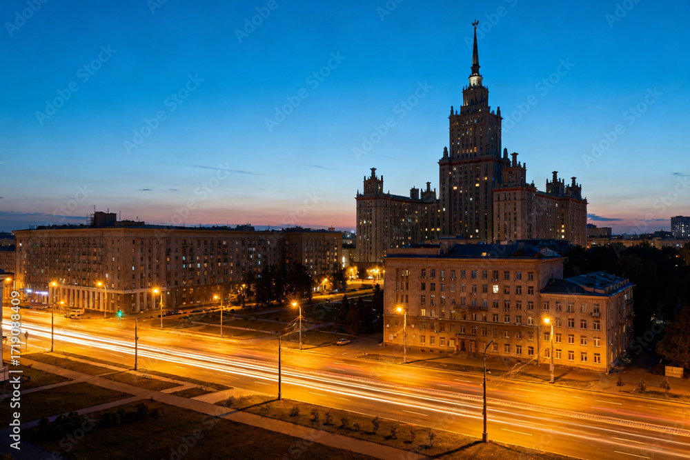 Fototapeta premium Cityscape at twilight with illuminated streets and a prominent high-rise building