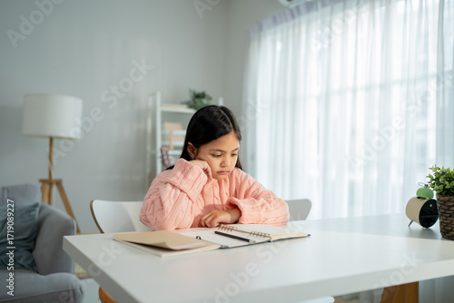 Foto Asian young kid girl struggling with homework in living room at home