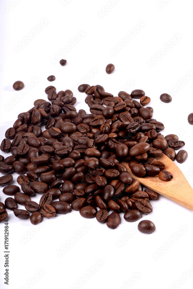 Obraz premium Close-up shot of roasted coffee beans scattered on a white surface with a wooden spoon.