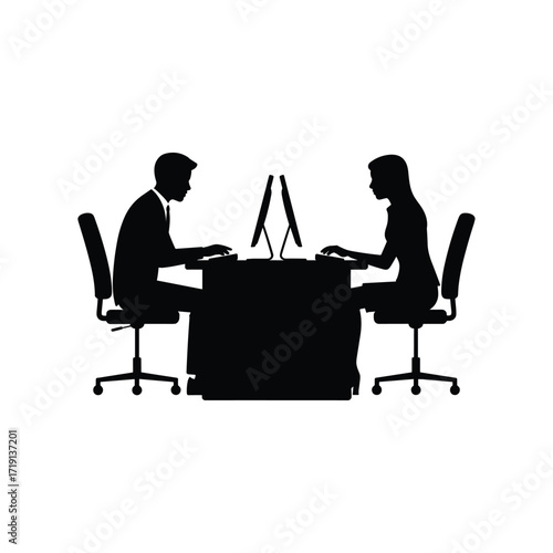 Silhouettes of business colleagues working on computers at a shared office desk