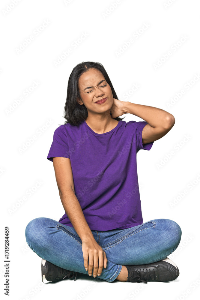 Fototapeta premium Latina sitting on floor in studio having a neck pain due to stress, massaging and touching it with hand.