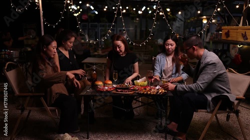 Happy Friends Celebrating Together at Night, Asian Group of Friends Having Fun and Toasting Drinks Outdoors, Enjoying a Celebration Concept.