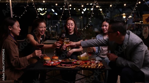 Happy Friends Celebrating Together at Night, Asian Group of Friends Having Fun and Toasting Drinks Outdoors, Enjoying a Celebration Concept.