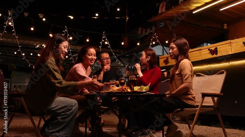 Happy Friends Celebrating Together at Night, Asian Group of Friends Having Fun and Toasting Drinks Outdoors, Enjoying a Celebration Concept.