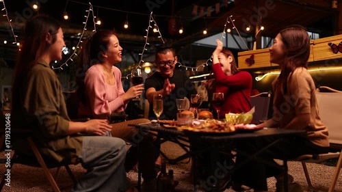 Happy Friends Celebrating Together at Night, Asian Group of Friends Having Fun and Toasting Drinks Outdoors, Enjoying a Celebration Concept.