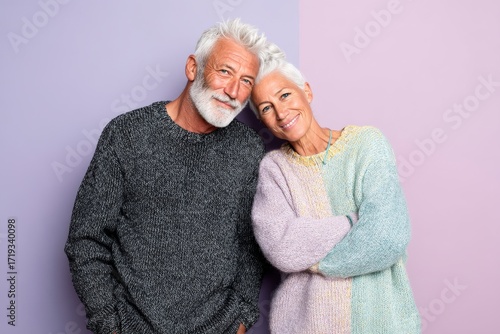 Portrait of a content latino couple in their 70s showing off a thermal merino wool top while standing against pastel or soft colors background