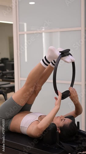 Athletic woman exercising on a pilates reformer with a ring.Vertical video