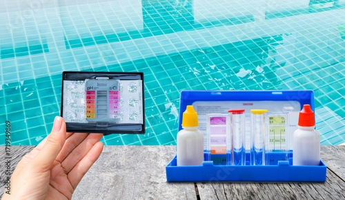 Water tester test kit on wooden table over blurred swimming pool water background, quality water testing test kit, pool maintenance and service business concept