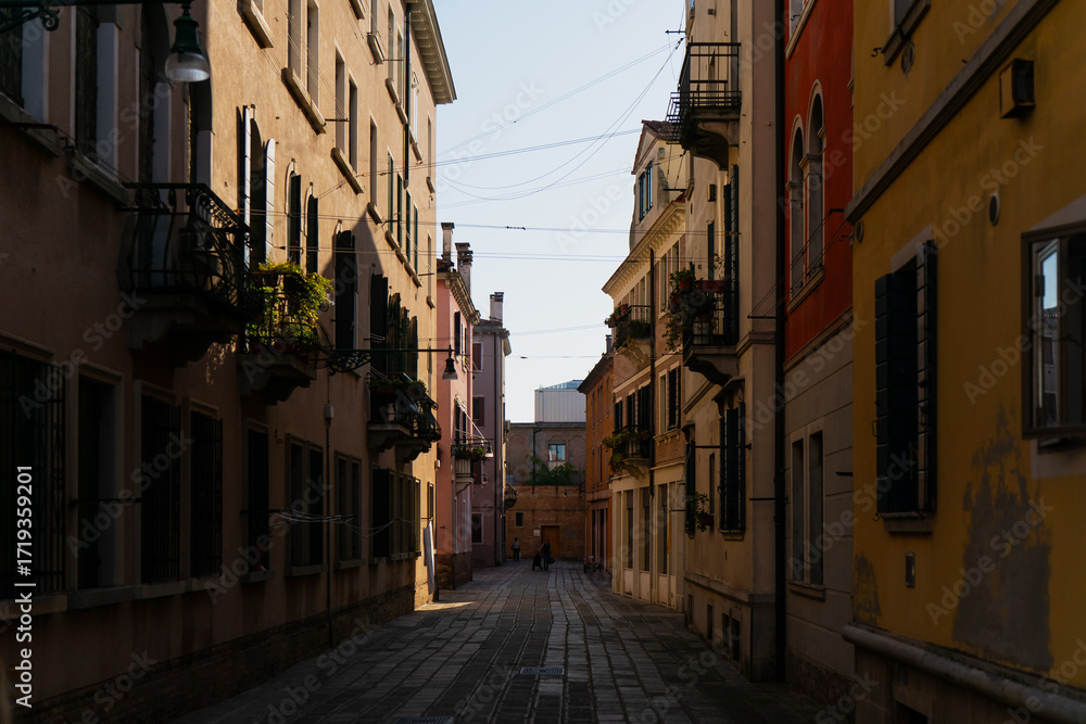 Naklejka premium Charming Venetian passageway lined with traditional architecture and colorful walls, creating a tranquil cityscape that highlights the unique atmosphere of Venice, Italy