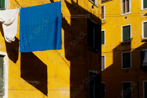 Foto Laundry drying in the sun on vivid yellow Venetian buildings, with strong blue a