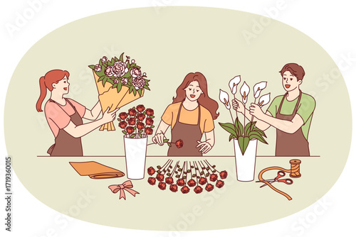 Flower shop employees collect festive bouquets for wedding or holiday party decoration. Man and two women working in flower shop create decorations from roses and lilies for event arrangements.