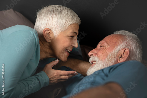 Portrait of happy senior couple smiling each other on bed