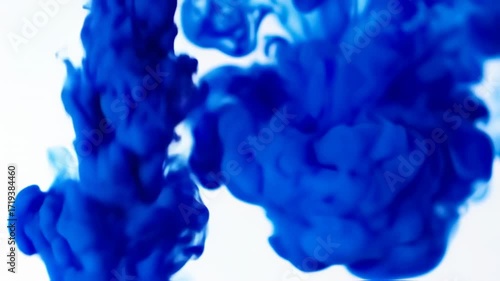 Abstract swirls of deep blue ink dissolving in white liquid