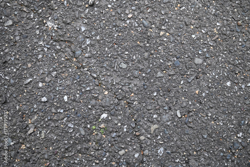 Texture, background of dark asphalt with small stones and cracks