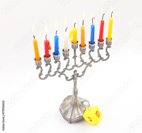 Hanukkah candles burn with dreidel, isolated over white