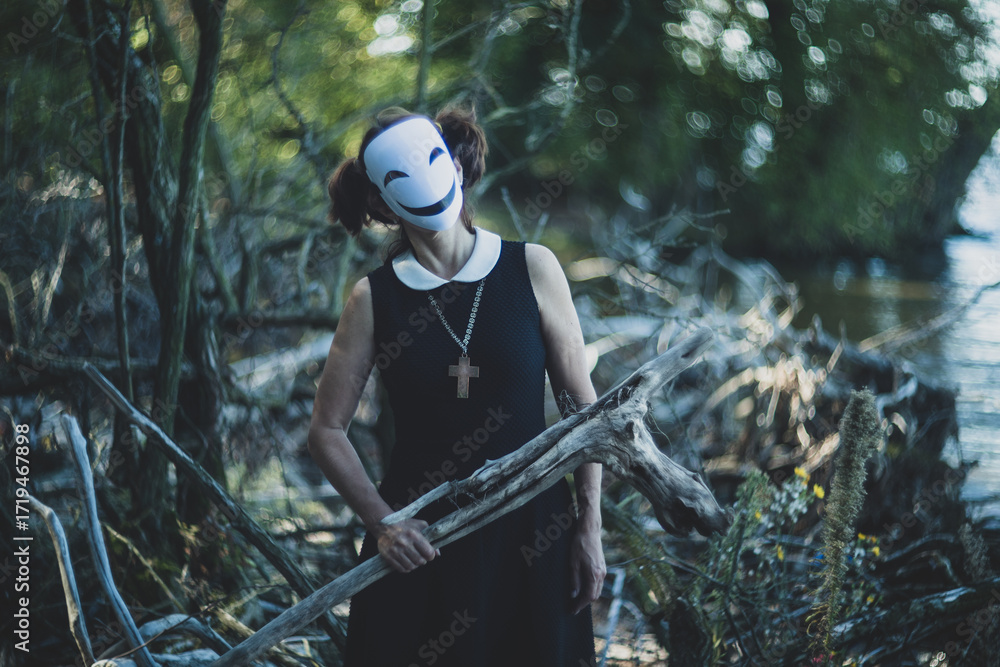 Fototapeta premium Masked schoolgirl in forest sitting quietly on autumn tree.