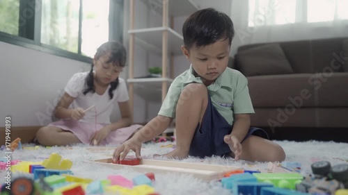Girls and boys are playing with toys in the room, and the children are playing with colorful toys on the carpet on the floor.