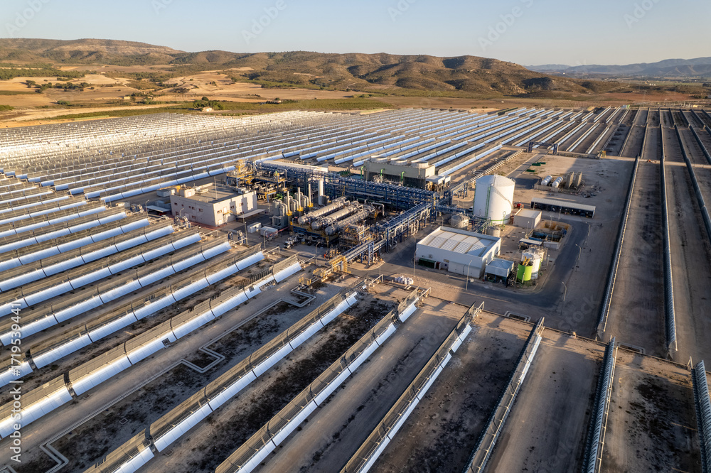 Fototapeta premium Solar thermal power station with rows of parabolic trough mirrors reflecting sunlight. Renewable energy facility showcases cutting-edge technology for sustainable electricity generation.
