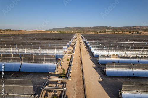 Solar thermal power station with rows of parabolic trough mirrors reflecting sunlight. Renewable energy facility showcases cutting-edge technology for sustainable electricity generation.