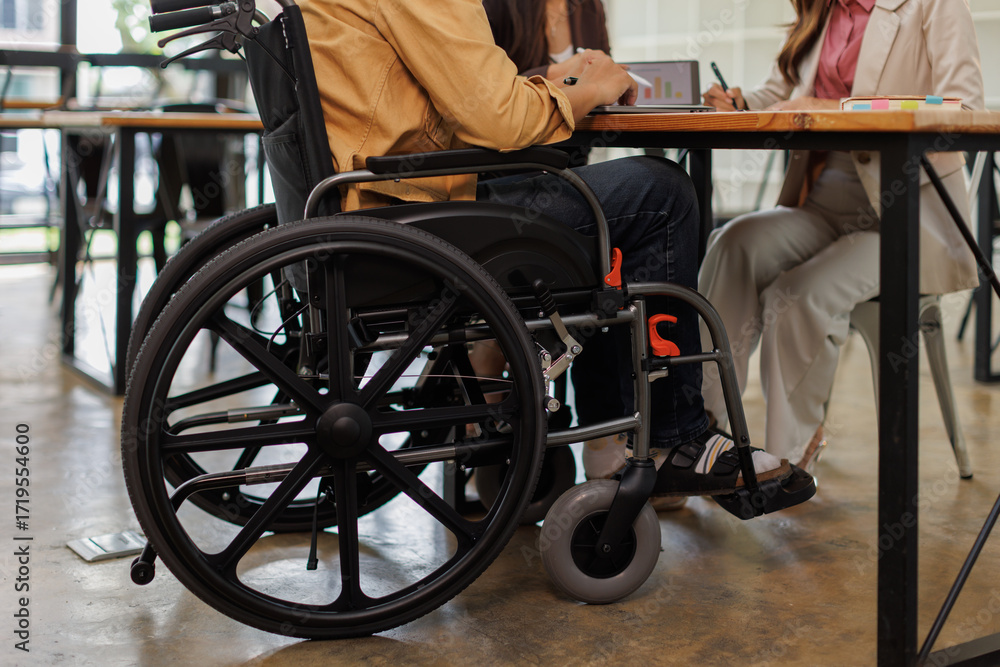 Obraz premium Group of business people in a meeting with man on a wheelchair for inclusion. Young businessman greeting business partner and team. Coworker on wheelchair