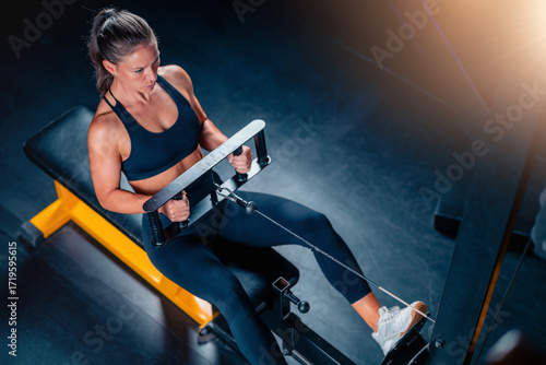 Engaging with gym machines, a woman improves power and flexibility. This focused workout supports health goals and enhances vitality with precise resistance-based training.
