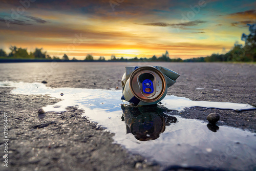 Fotografía Canned drink spilled on asphalt road on sunset landscape in serene outdoor setting