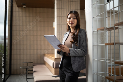 Tableau sur toile Professional businesswoman in blazer using tablet for work, looking ahead with thoughtful expression